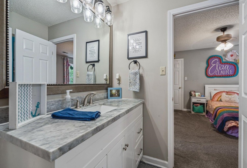 Ensuite bathroom with a textured ceiling, vanity, and dark carpet