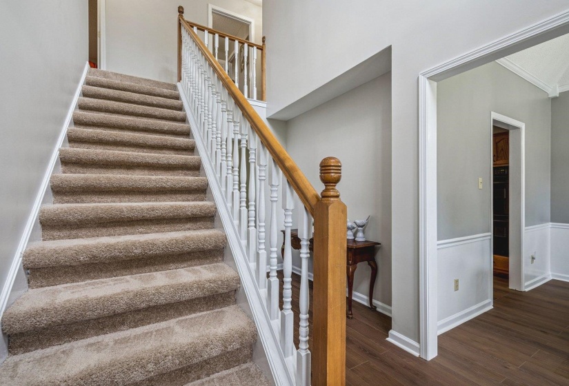 Stairs with wood finished floors and crown molding