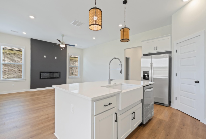 Kitchen island with a white farmhouse sink, stainless steel faucet, and white countertop