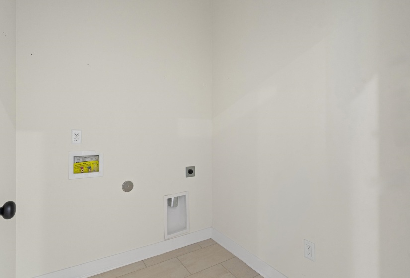 Laundry area with tile flooring and white baseboards