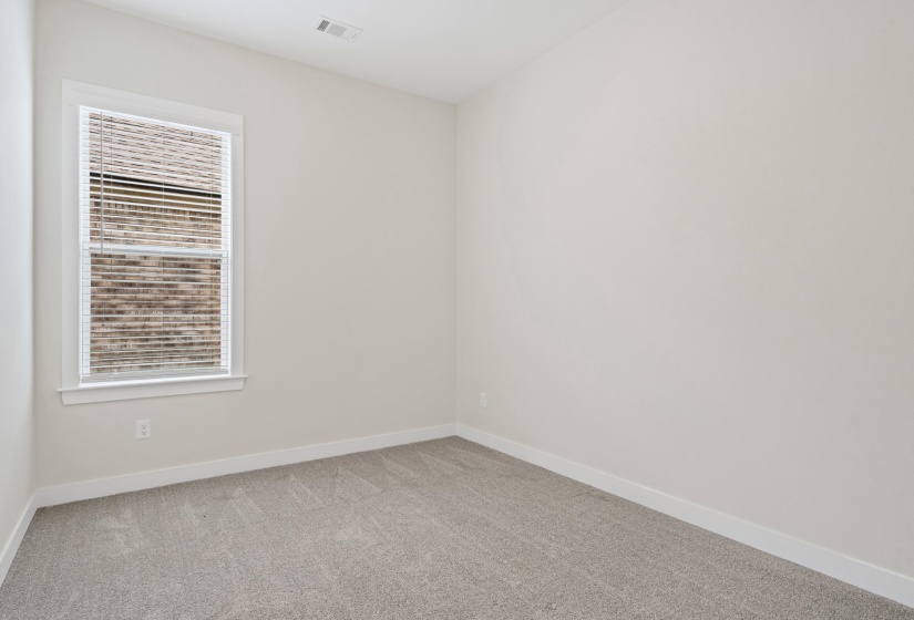 Neutral-toned room featuring a single window with blinds, light gray carpet, and white baseboards