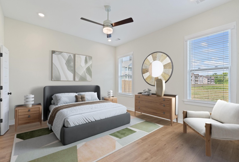 Bright bedroom featuring wood-finish flooring, two window openings, and a ceiling fan with integrated lighting