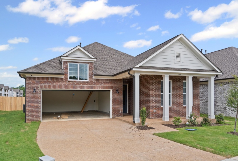 Brick exterior featuring a covered entry with white columns, an attached garage, and a dormer window above the garage