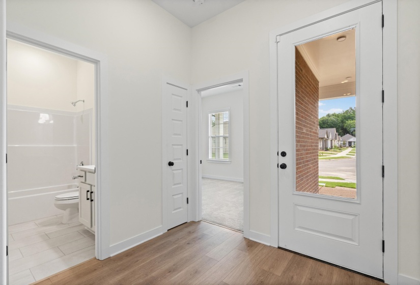 Entryway featuring wood-finish flooring, a white paneled door with a full-length glass insert, and matte black hardware