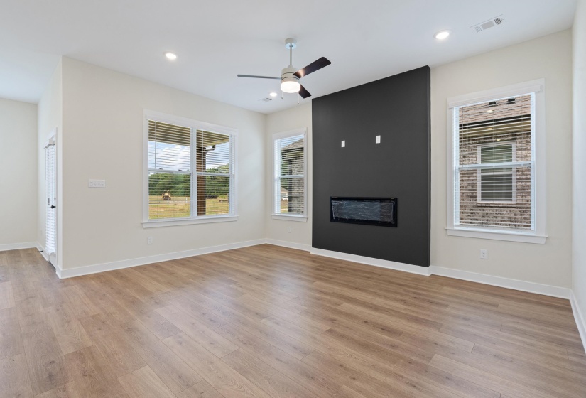 Living area featuring wood-finish flooring, an accent wall with a built-in electric fireplace, a ceiling fan with integrated lighting, and recessed ceiling lights
