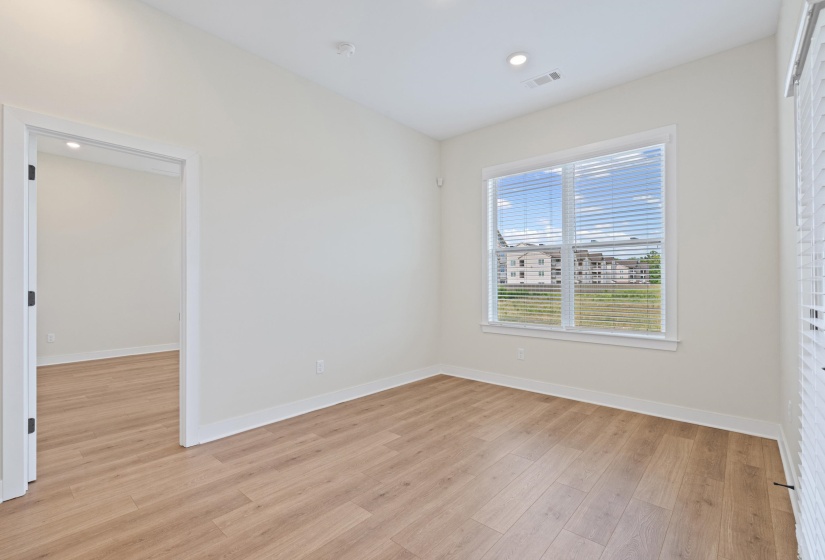 Room featuring wood-finish flooring, recessed lighting, and a large window with horizontal blinds