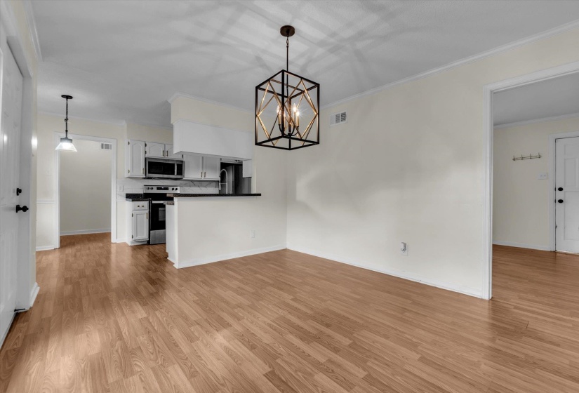 Unfurnished dining area with suspended lighting, ornamental molding, and light wood-type flooring
