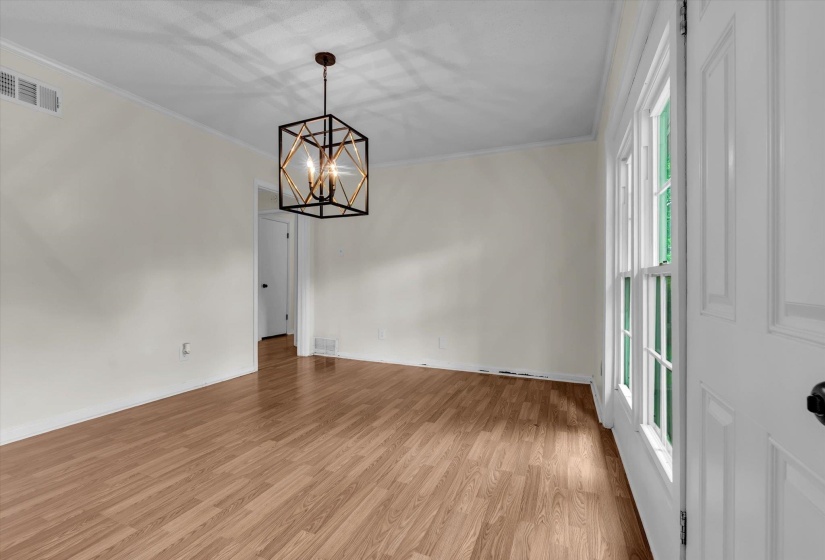 Unfurnished room featuring crown molding, light wood finished floors, and hanging lights