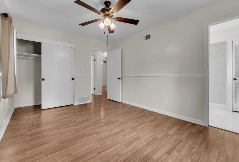 Unfurnished bedroom featuring light wood-style flooring, a ceiling fan, a closet, and connected bathroom