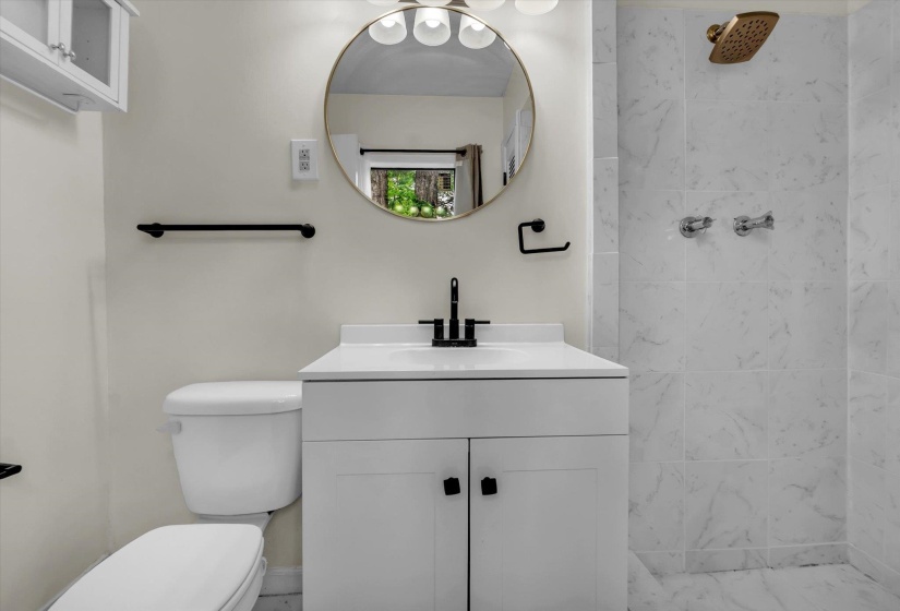 Bathroom featuring tiled shower and vanity