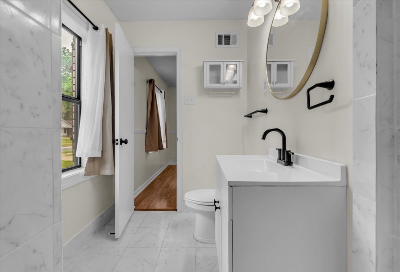 Half bathroom featuring vanity, light marble finish floors, and plenty of natural light