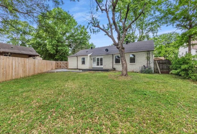 Back of property featuring a gate, a fenced backyard, brick siding, and a patio