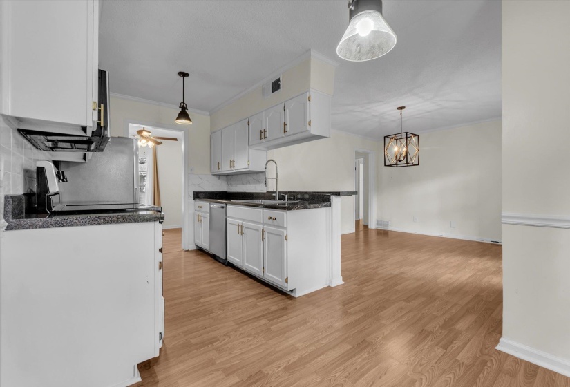 Kitchen featuring decorative backsplash, light wood-type flooring, crown molding, white cabinetry, and stainless steel appliances