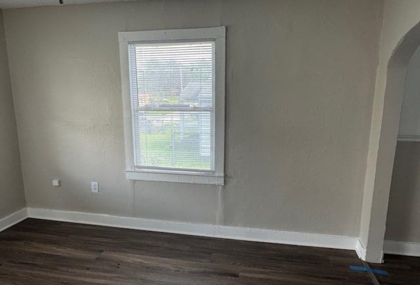 Spare room with a textured wall, arched walkways, dark wood-type flooring, and baseboards