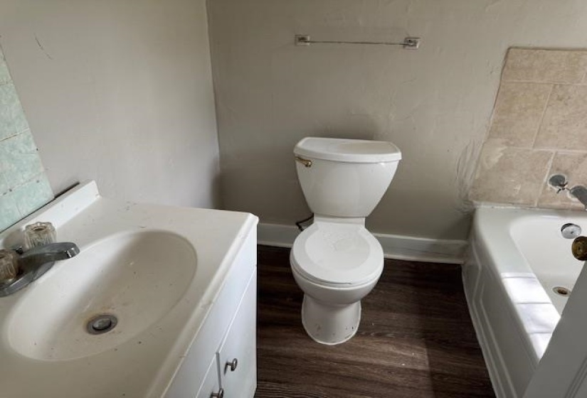 Full bathroom featuring vanity, baseboards, a bathing tub, toilet, and wood finished floors