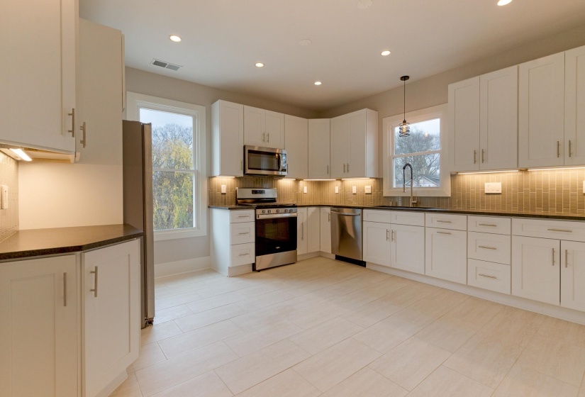 Kitchen featuring stainless steel appliances, hanging light fixtures, recessed lighting, white cabinetry, and backsplash