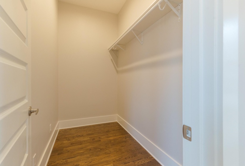 Walk in closet with dark wood-style flooring