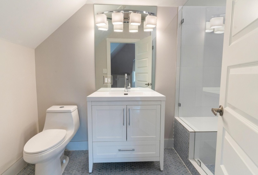 Bathroom featuring vanity, a stall shower, vaulted ceiling, and dark tile patterned flooring