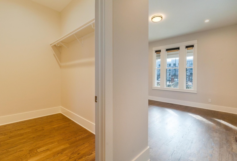 Walk in closet with dark wood-style floors