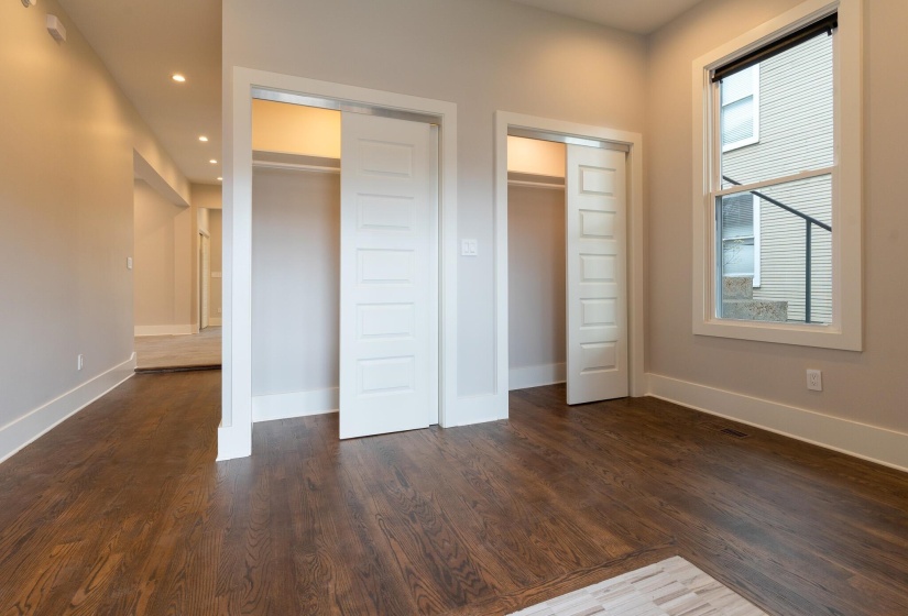 Unfurnished bedroom with dark wood-style floors and two closets