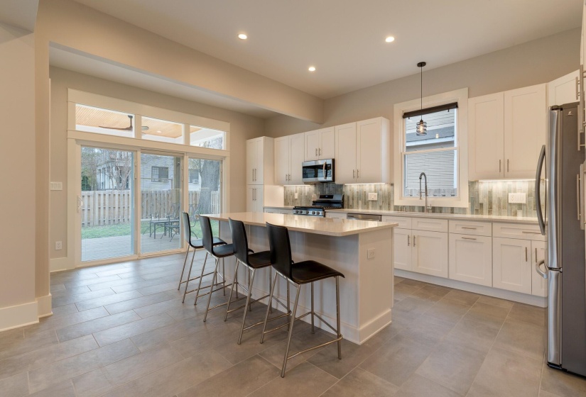 Kitchen with white cabinetry, a center island, a breakfast bar area, decorative backsplash, and appliances with stainless steel finishes
