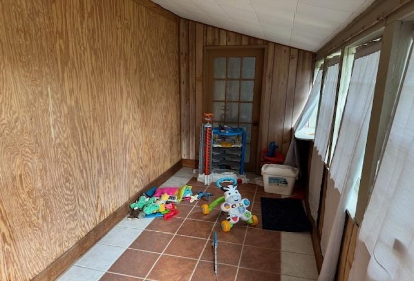 Playroom with lofted ceiling, wood walls, and tile patterned floors
