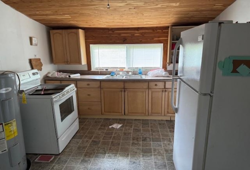 Kitchen with white appliances, electric water heater, wooden ceiling, and light wood finish cabinetry