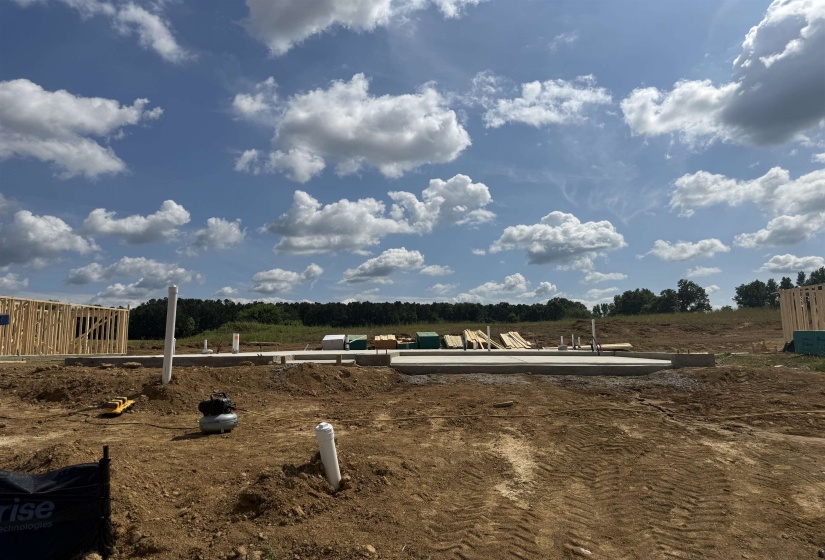 Cleared and graded lot with a concrete foundation and visible plumbing rough-ins