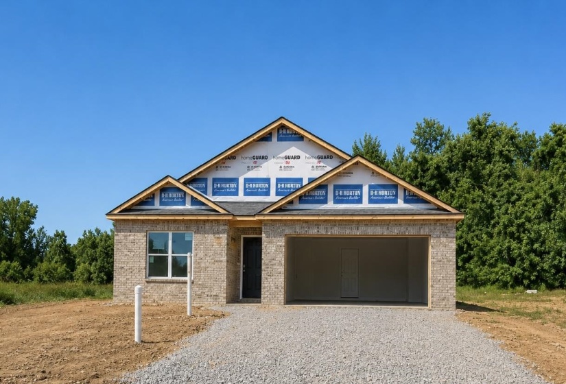 Newly constructed residence featuring a light-colored brick facade, a dark shingle roof, a two-car garage opening, and a gravel driveway