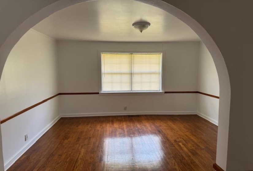 Empty room with arched walkways and dark wood finished floors