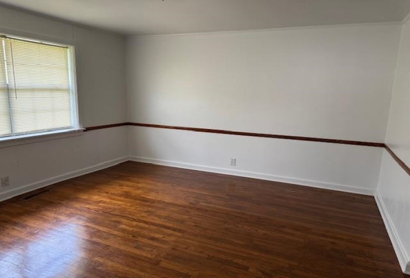 Empty room featuring dark wood-style floors and baseboards