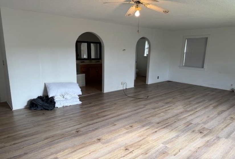Empty room featuring light wood-type flooring, a ceiling fan, a textured ceiling, and arched walkways
