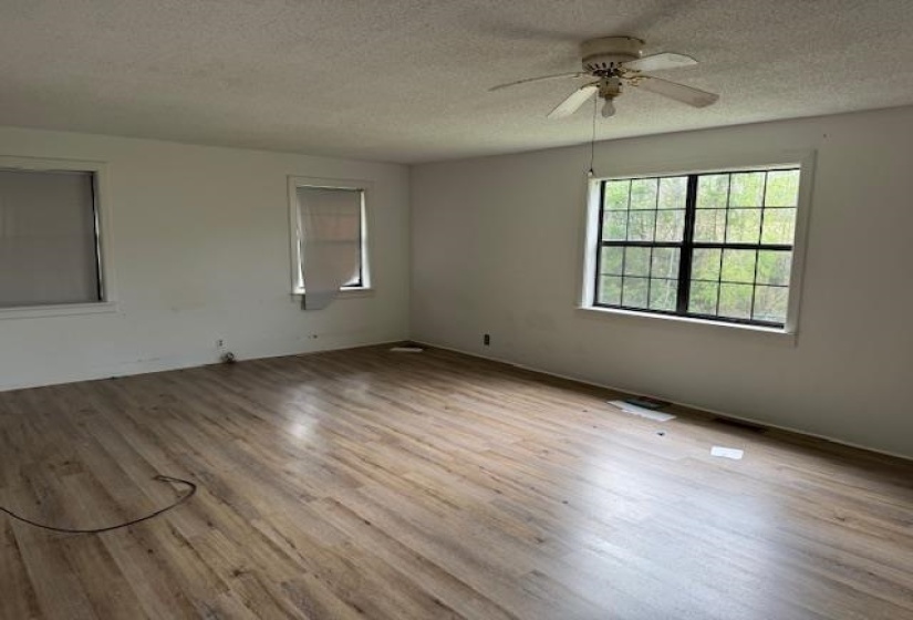 Spare room featuring light wood-style floors, a textured ceiling, and a ceiling fan