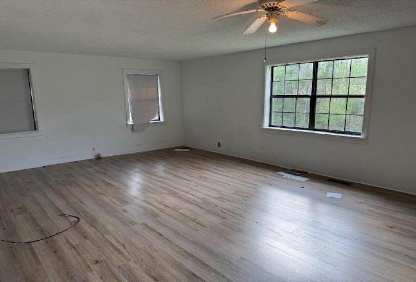 Spare room featuring light wood finished floors, a textured ceiling, and ceiling fan