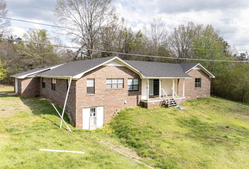 Single story home with brick siding, covered porch, a front yard, and a shingled roof