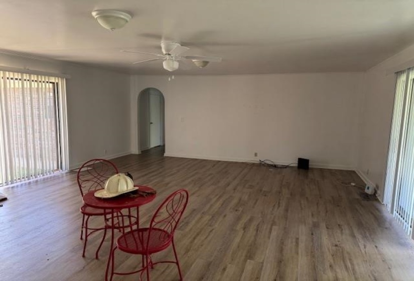 Unfurnished living room with plenty of natural light, a ceiling fan, wood finished floors, and arched walkways