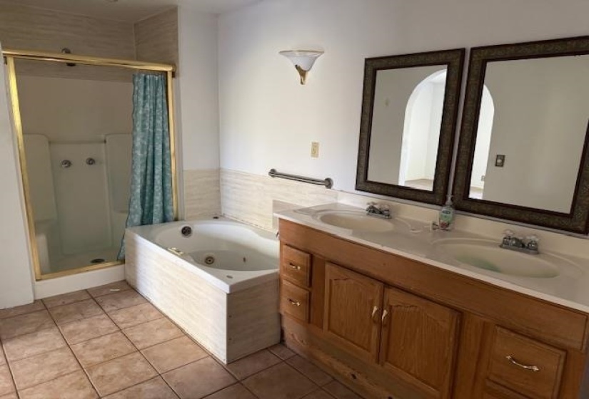 Bathroom with double vanity, a jetted tub, light tile patterned floors, and a shower stall