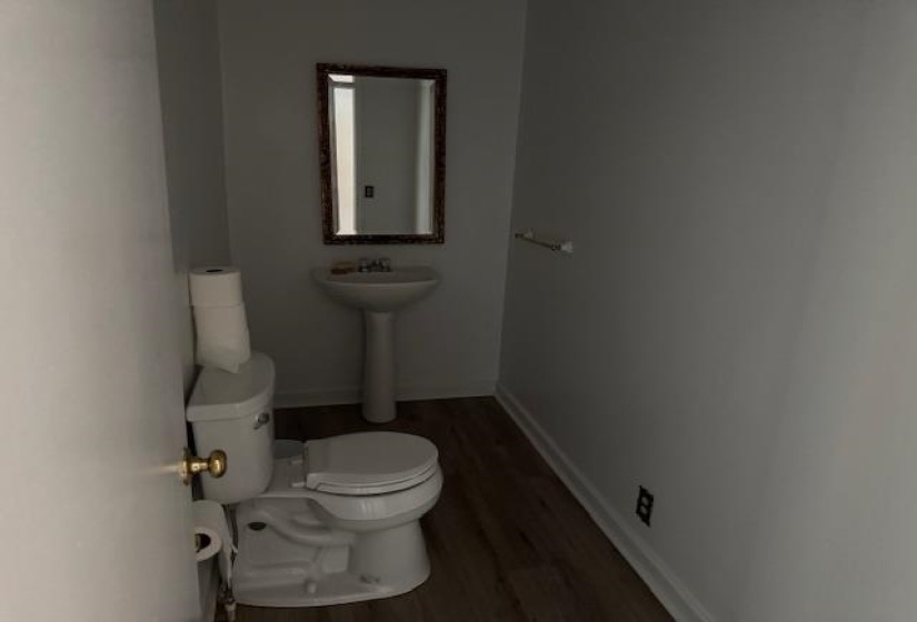 Half bathroom featuring toilet and wood finished floors