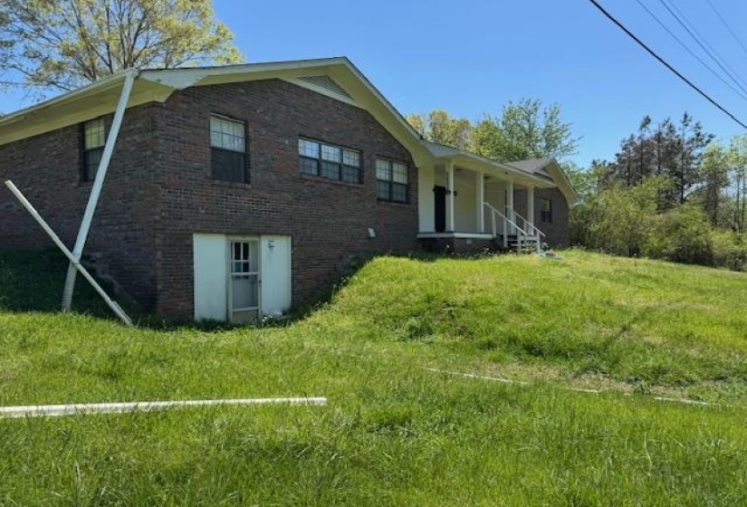 Rear view of property with a lawn, brick siding, and covered porch