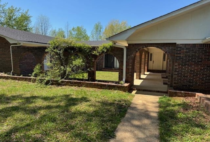 Property entrance with brick siding and a lawn