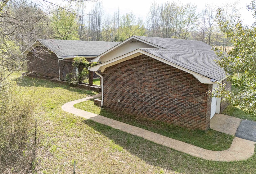 View of property exterior featuring a yard, brick siding, and roof with shingles