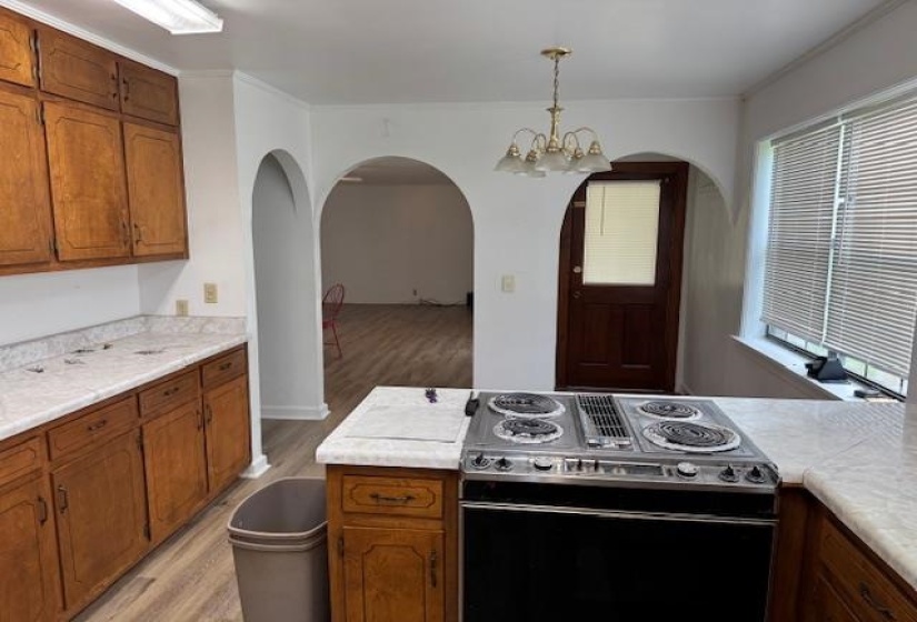 Kitchen with stainless steel electric stove, wood finish cabinetry, a chandelier, and light countertops
