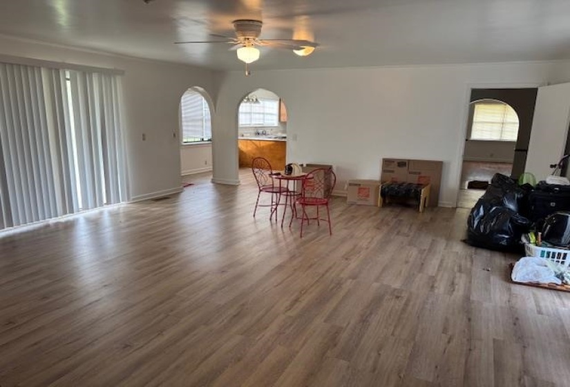 Dining space with wood finished floors, a ceiling fan, and arched walkways