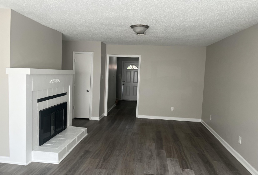 Unfurnished living room with a glass covered fireplace, dark wood-style floors, and a textured ceiling