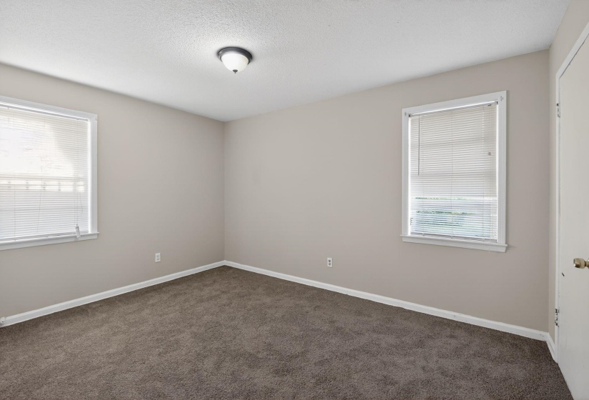 Empty room featuring dark carpet and a textured ceiling