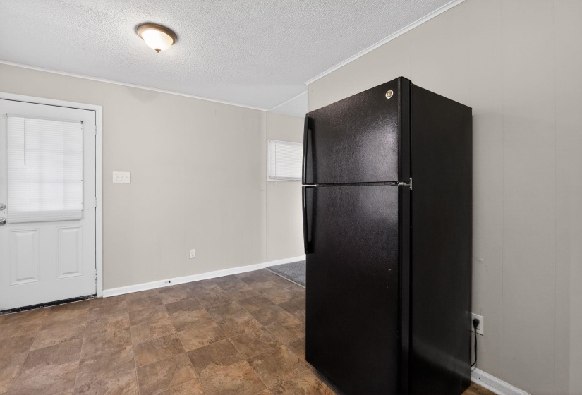 Kitchen featuring freestanding refrigerator, a textured ceiling, stone finish floors, and ornamental molding