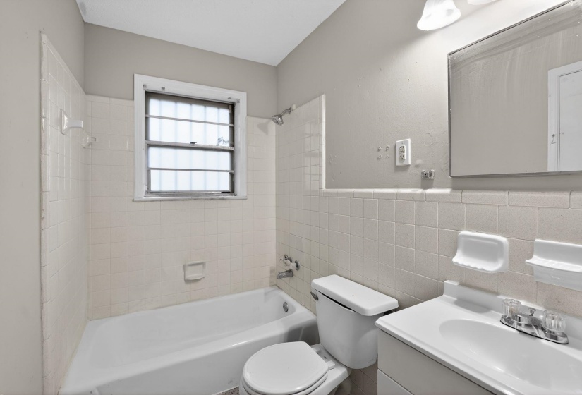 Full bathroom with vanity, tub / shower combination, tile walls, and a wainscoted wall
