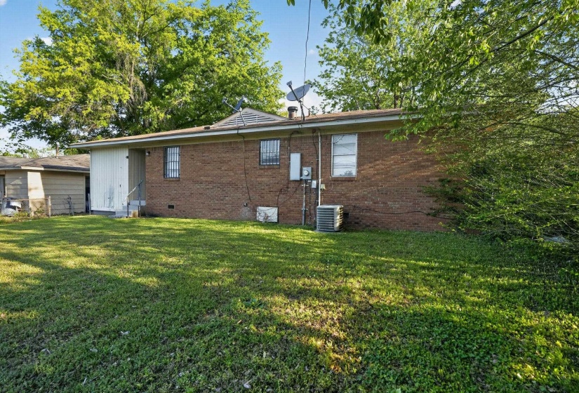 Rear view of property featuring crawl space, brick siding, and a yard