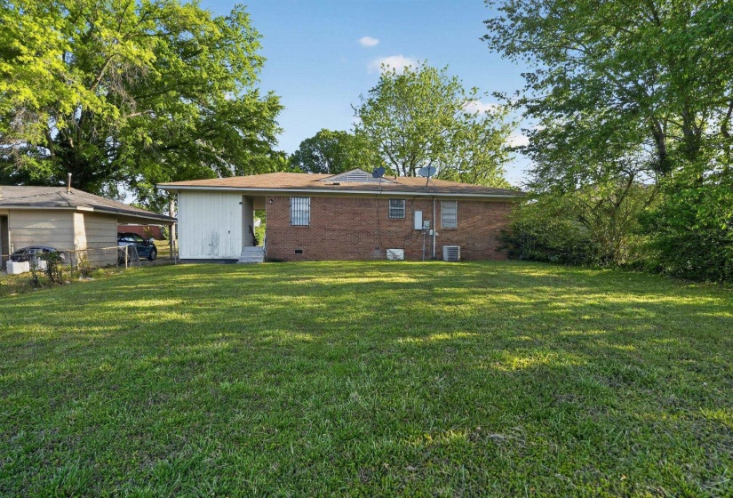 Rear view of property featuring a lawn, brick siding, and crawl space