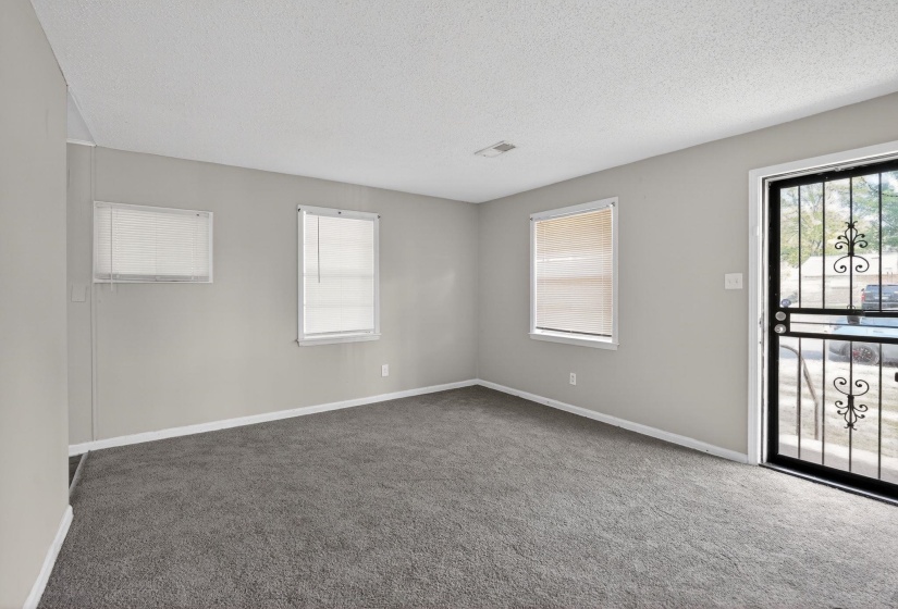 Empty room with dark colored carpet and a textured ceiling